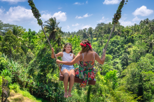 travelers enjoying a rope swing above the treetops in a tropical paradise.
